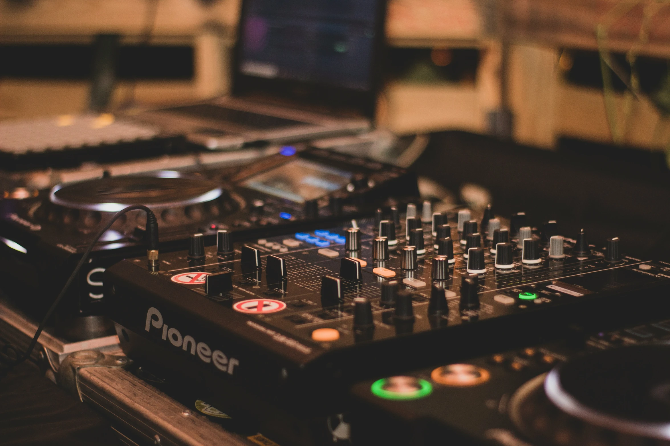 a dj mixing machine with a laptop in the background