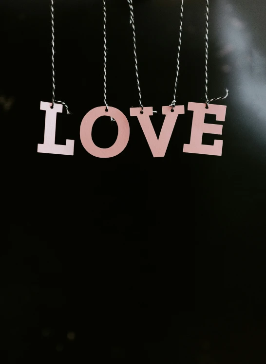 a wooden cutout of a heart that says love hangs from a chain