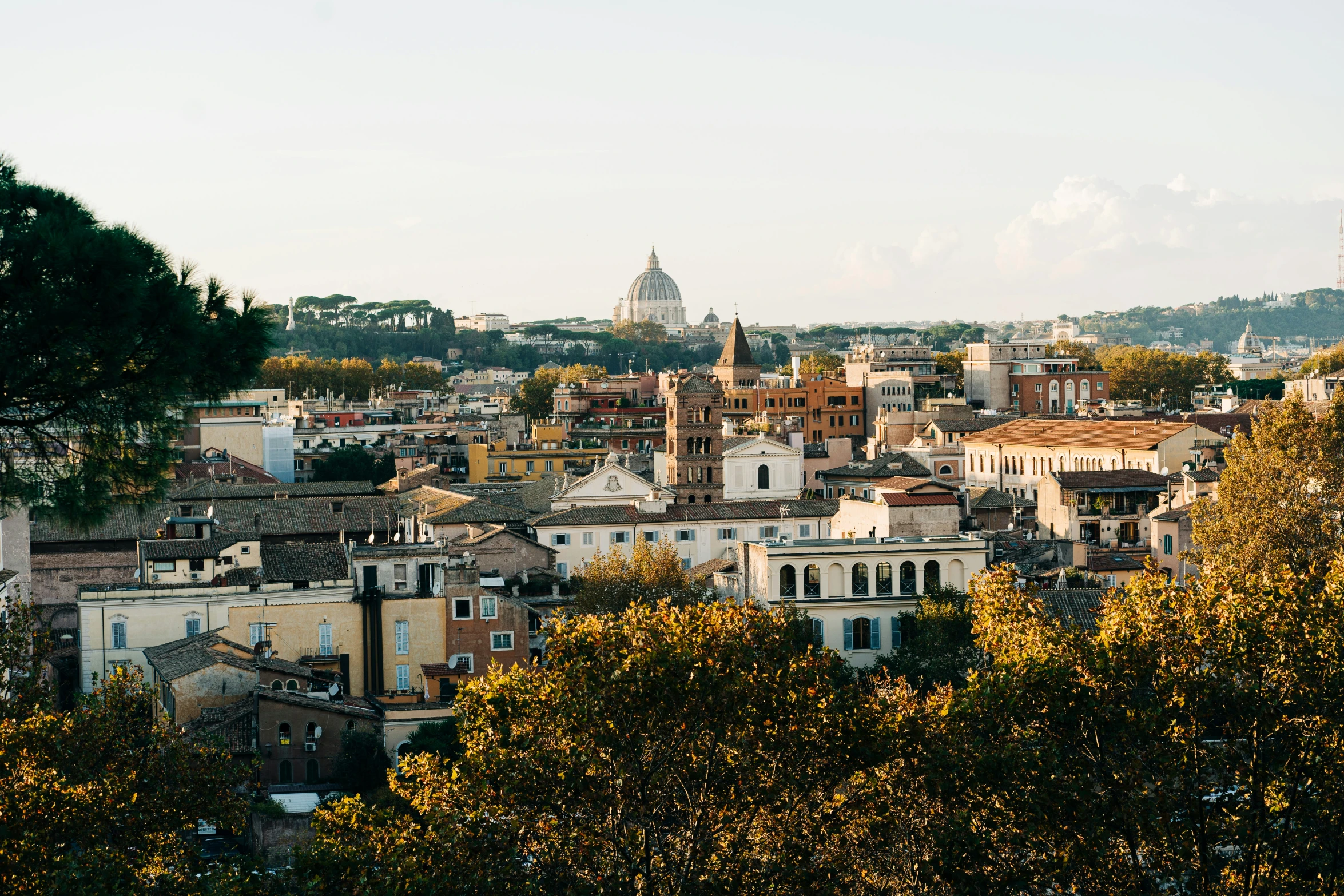 a scenic view of the city with a church steeple and trees in front