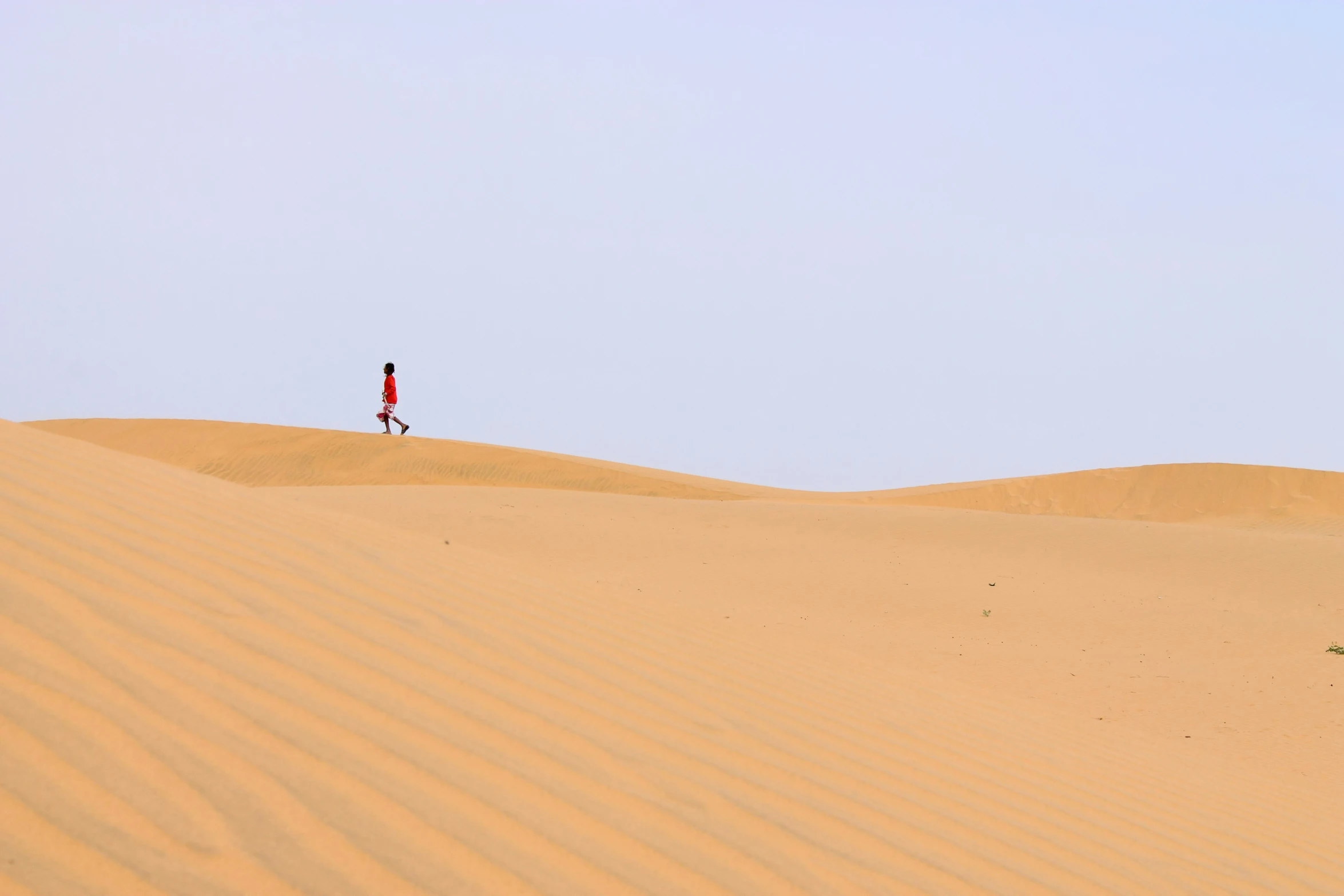 a person walking down a desert field wearing red