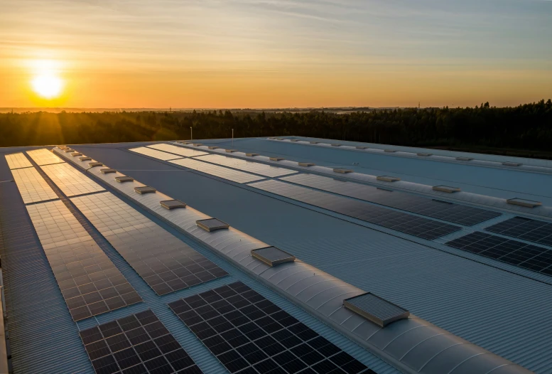 sun setting behind the roof of a large solar power plant