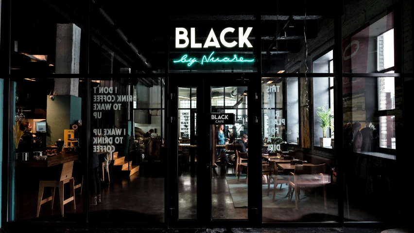 the front entrance to a black restaurant with glass walls