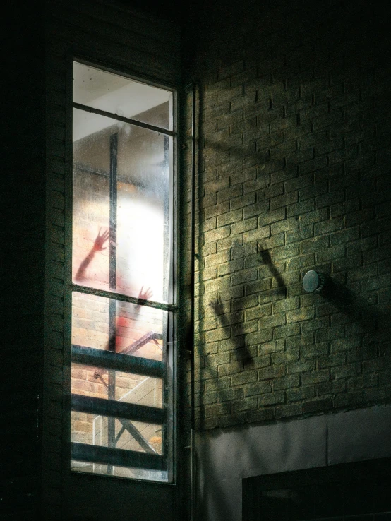 the silhouettes of people in a window near a brick wall