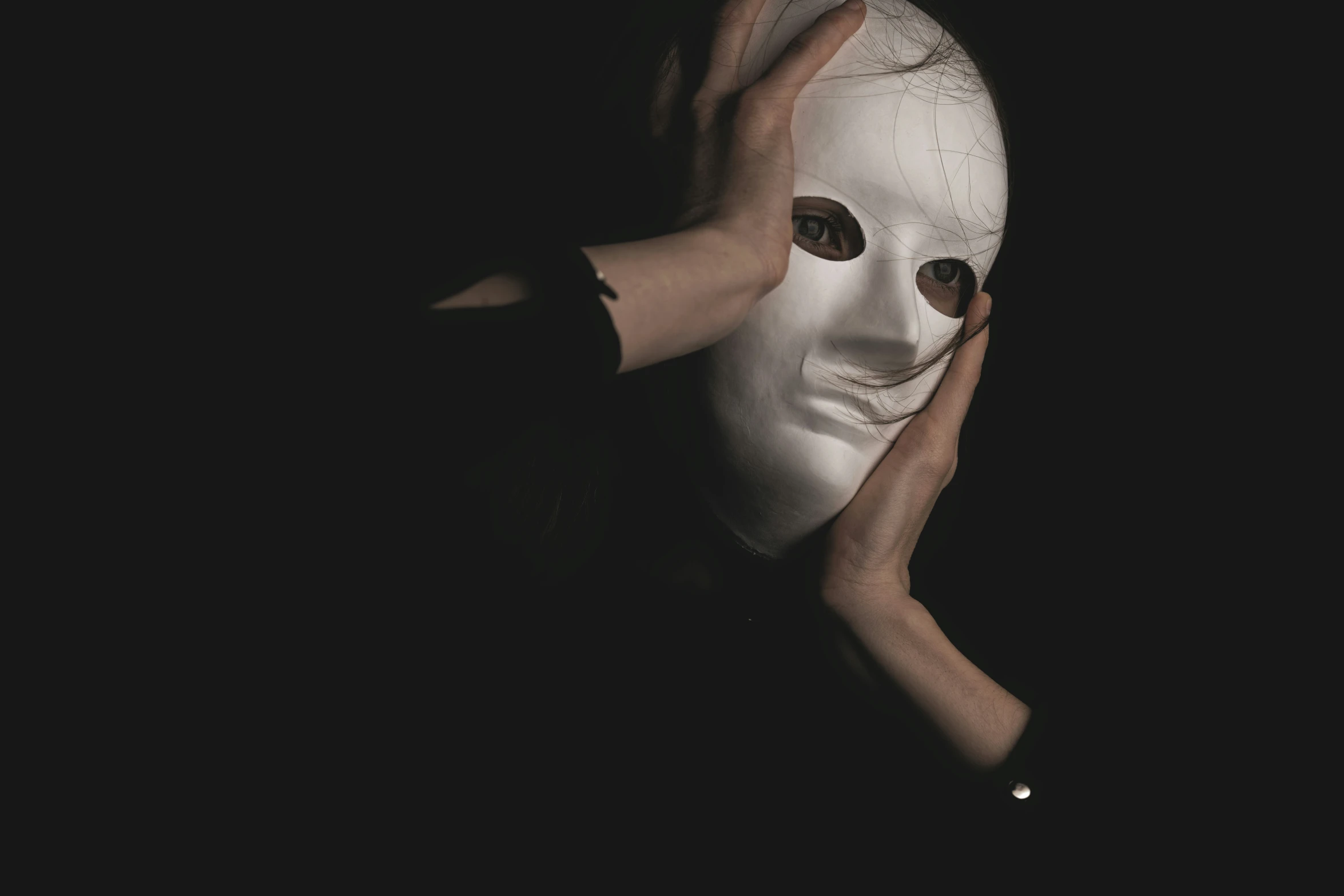 a hand that is holding up a mask with eyes