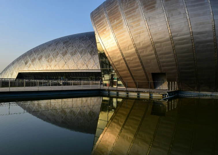 the building has a large metal structure that is reflecting in the water