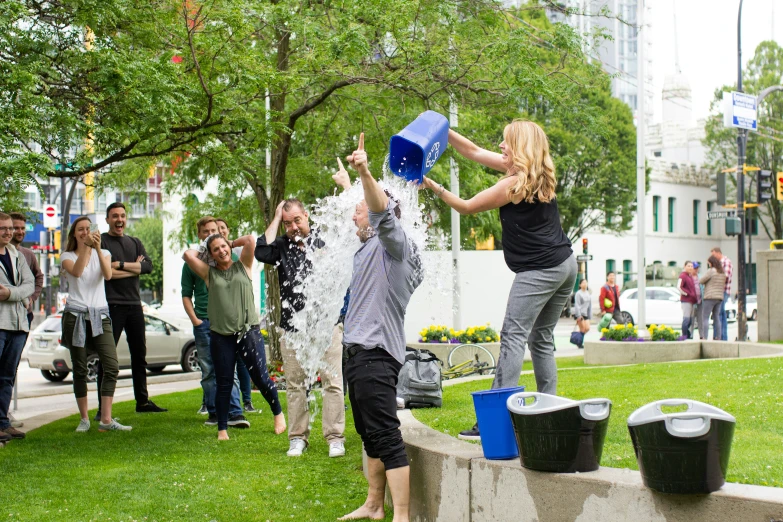 woman pouring water onto her face as friends watch