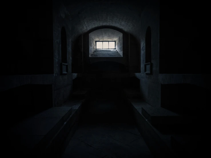 a dark hallway with a person standing in the window at one end