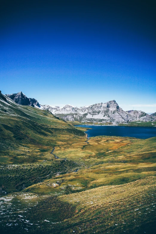 the mountains are dotted with grass and a body of water