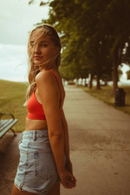 the woman stands near the park bench posing