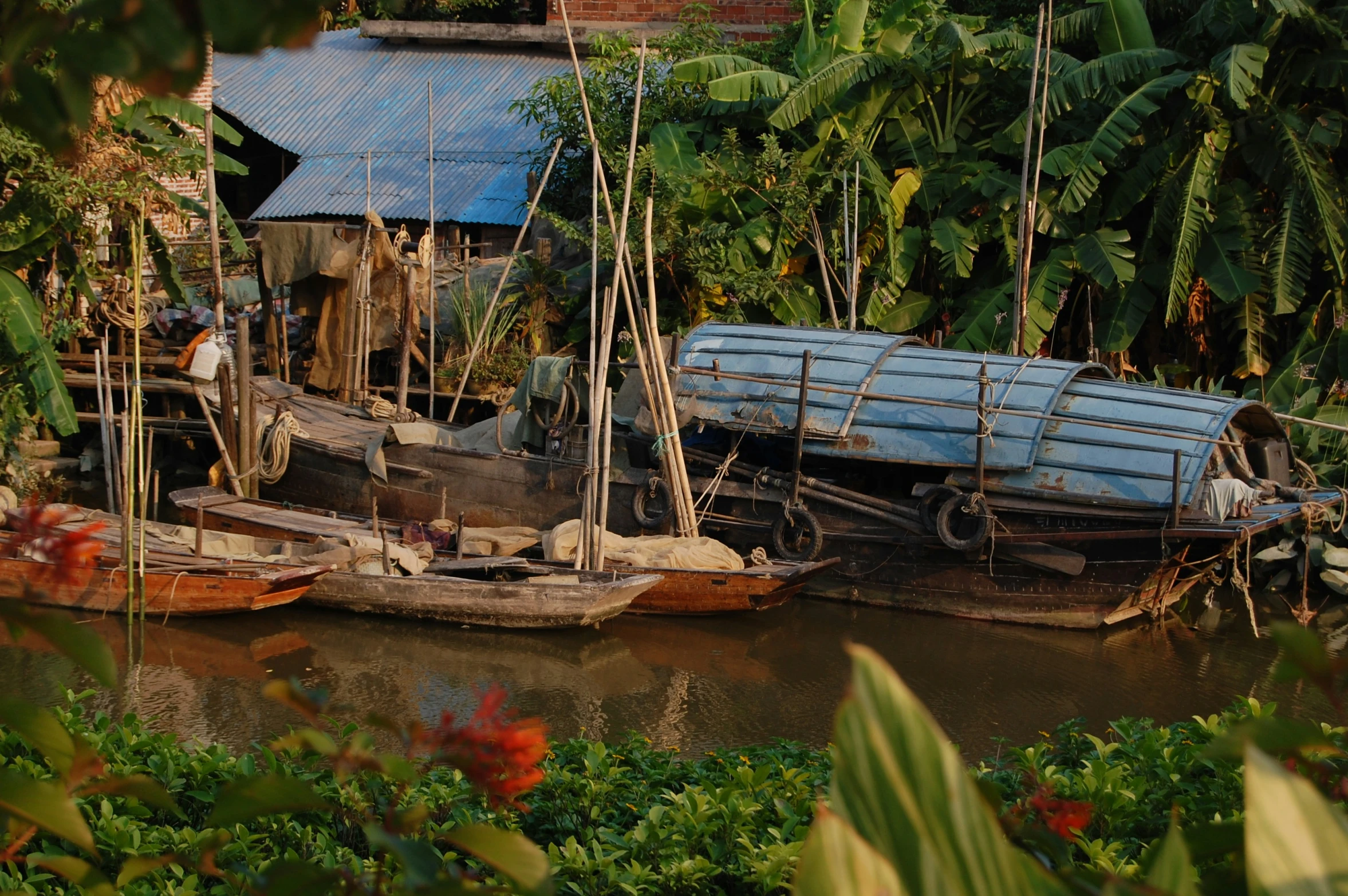 three wooden boats are parked at the edge of the river