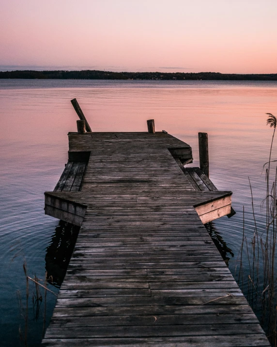 an empty pier on the water during sunset