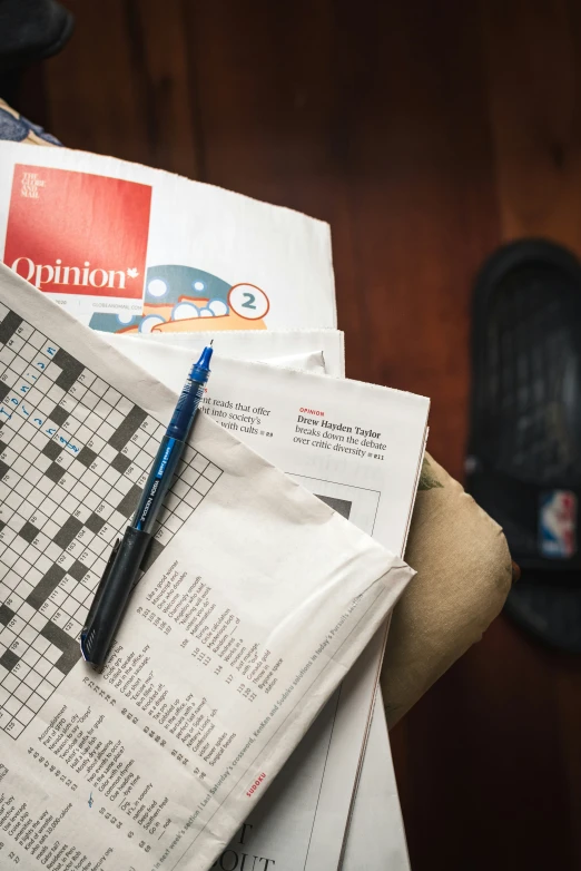 a crossword puzzle on some newspaper next to a black cup