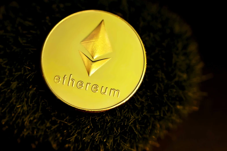 a gold colored ether coin that is on the grass