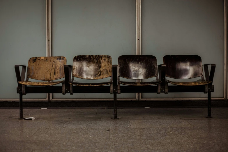 four brown chairs lined up against a wall