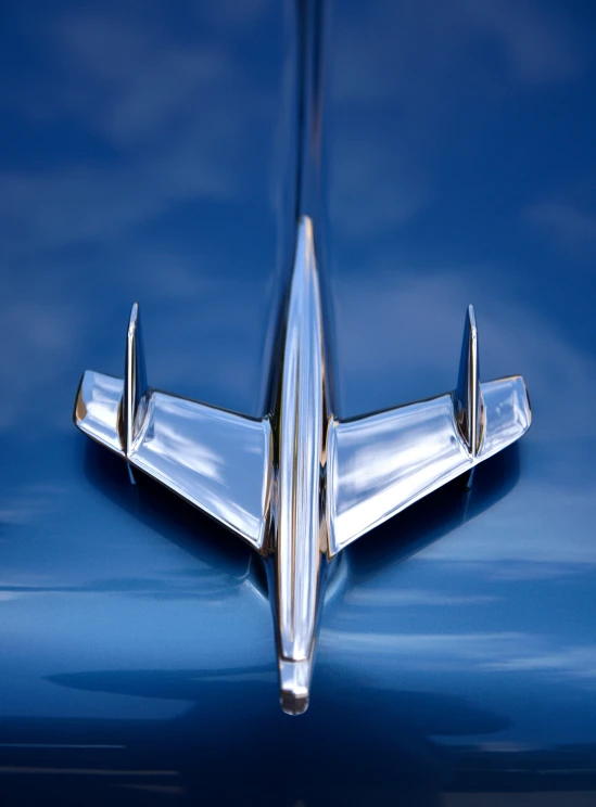 a shiny silver car emblem sits on the hood