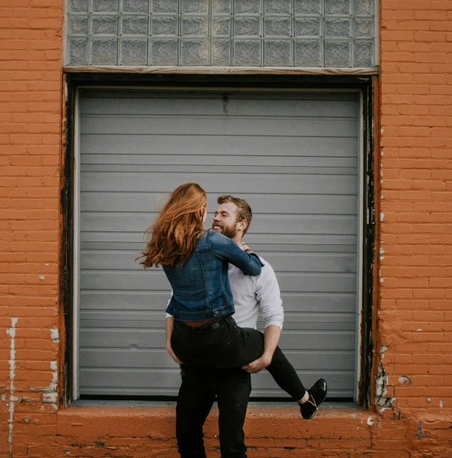 a young couple is pictured in front of a garage door