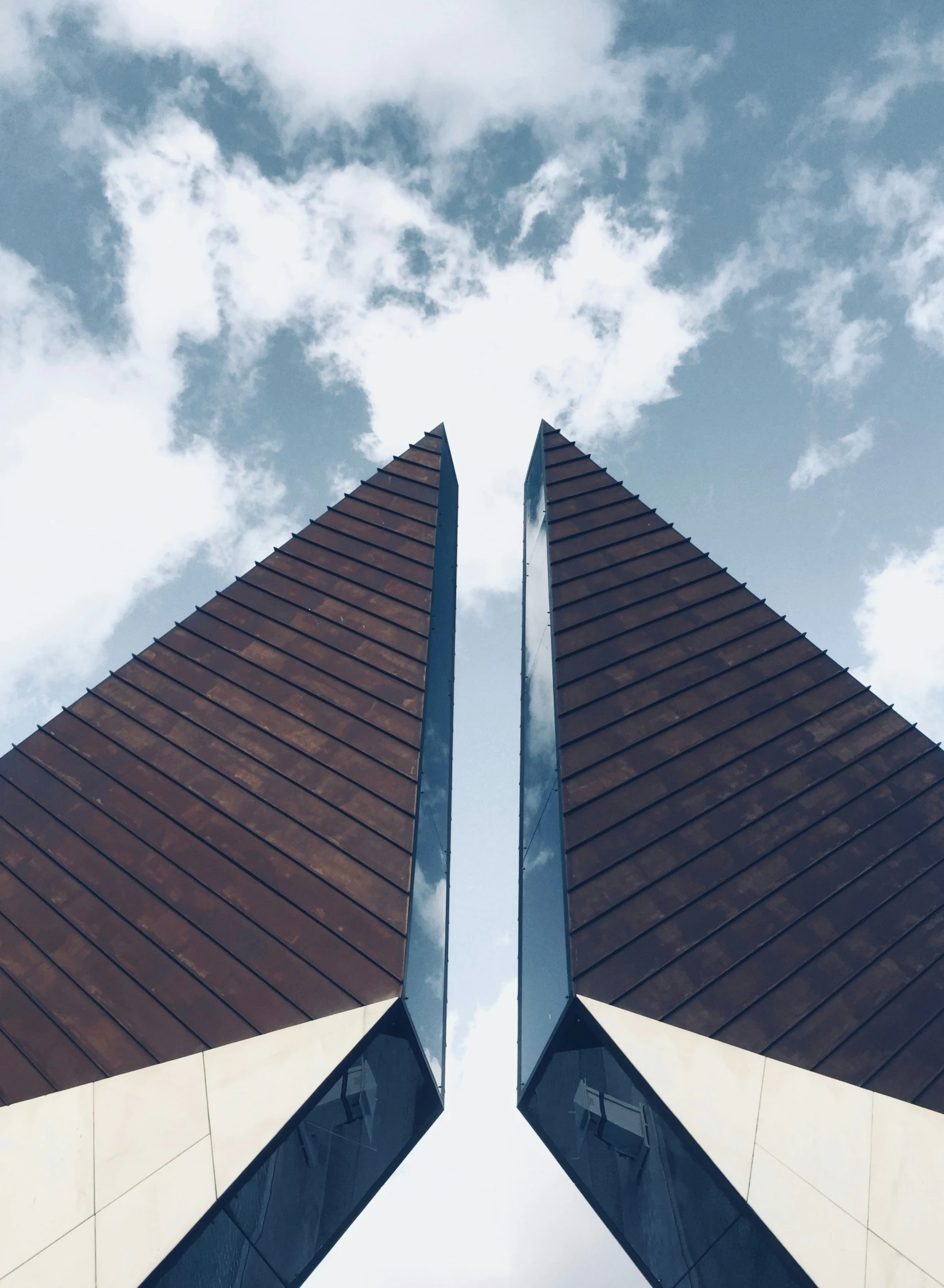 two very tall modern building structures under a cloudy sky