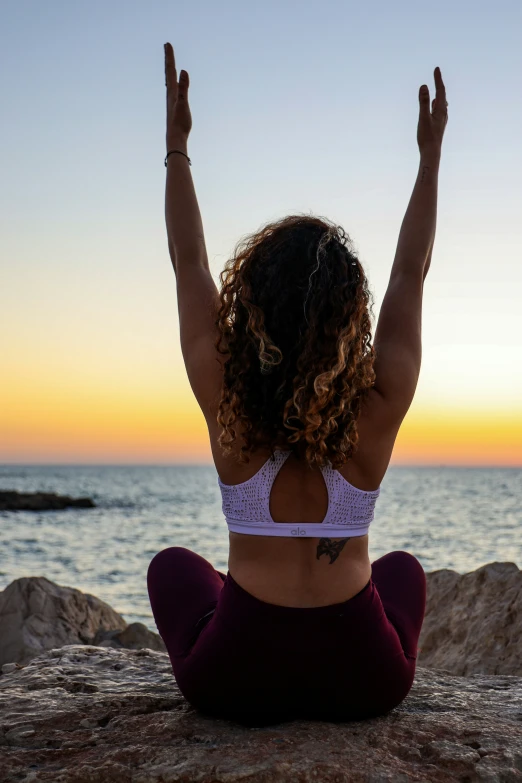 a woman is practicing yoga by the water