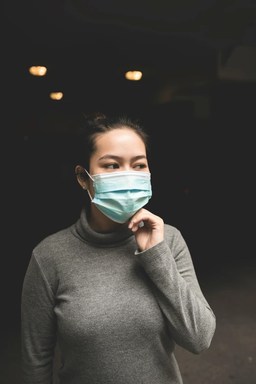 a woman wearing a face mask and looking off into the distance