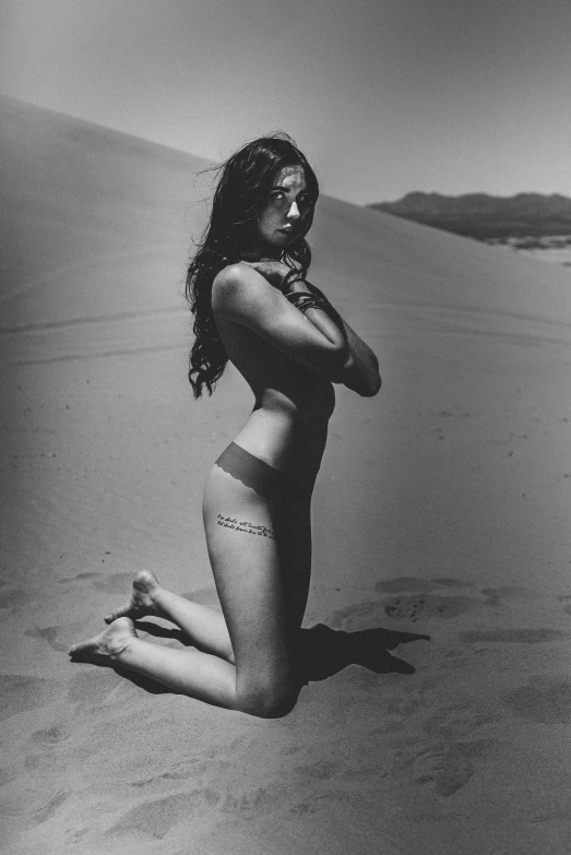 woman in bikini sitting on beach next to body in water