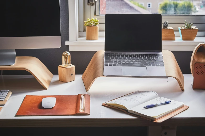 a table with a laptop a notebook and two cups