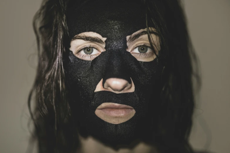 the woman is painted black and has one face covered in black facial mask