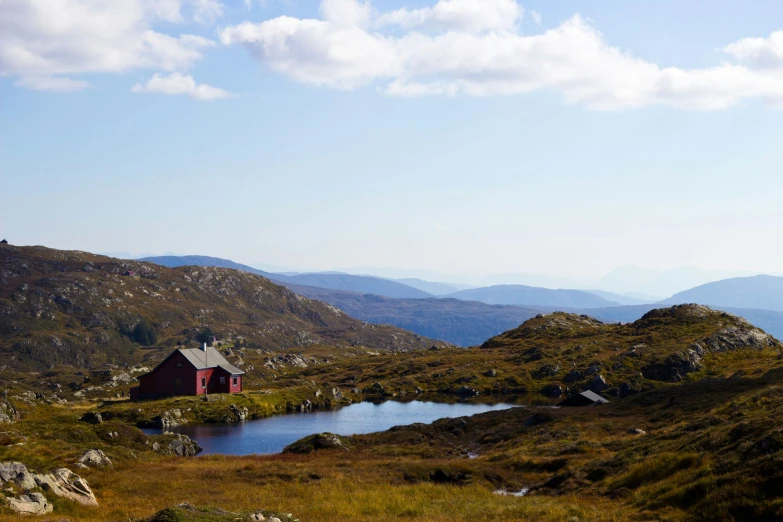 a mountain landscape with a cabin and lake in it