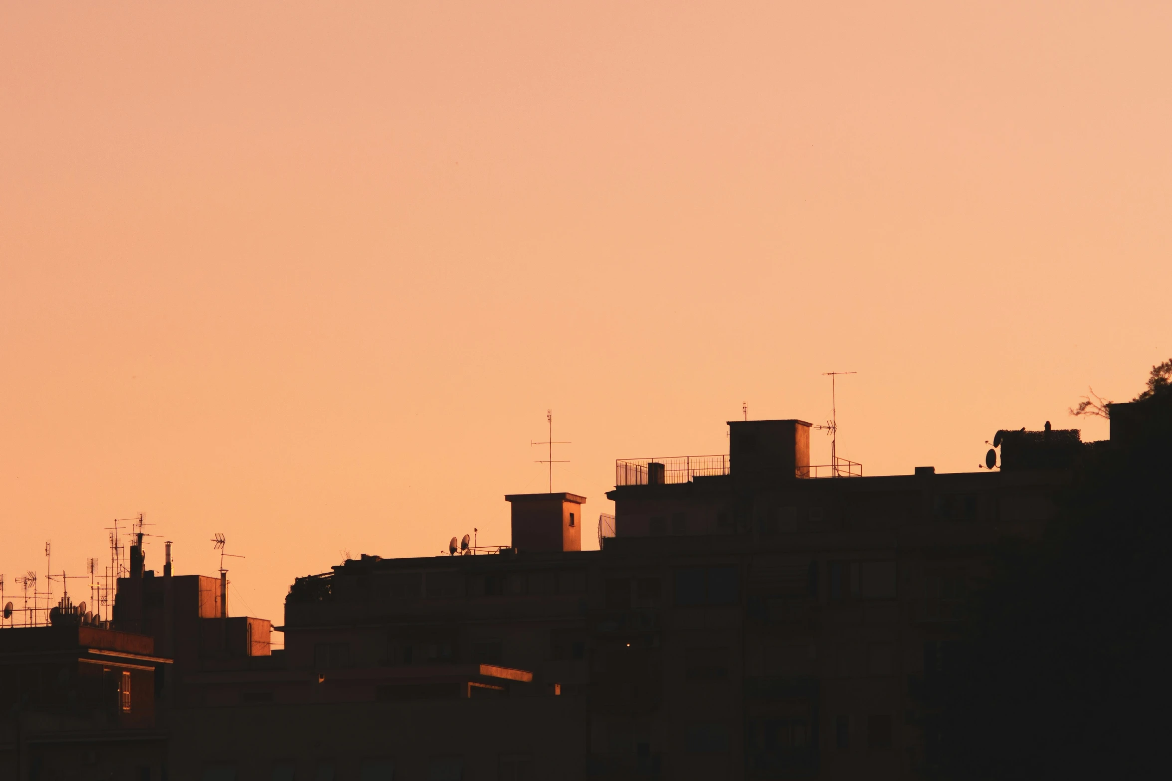 a plane flying near buildings during sunset