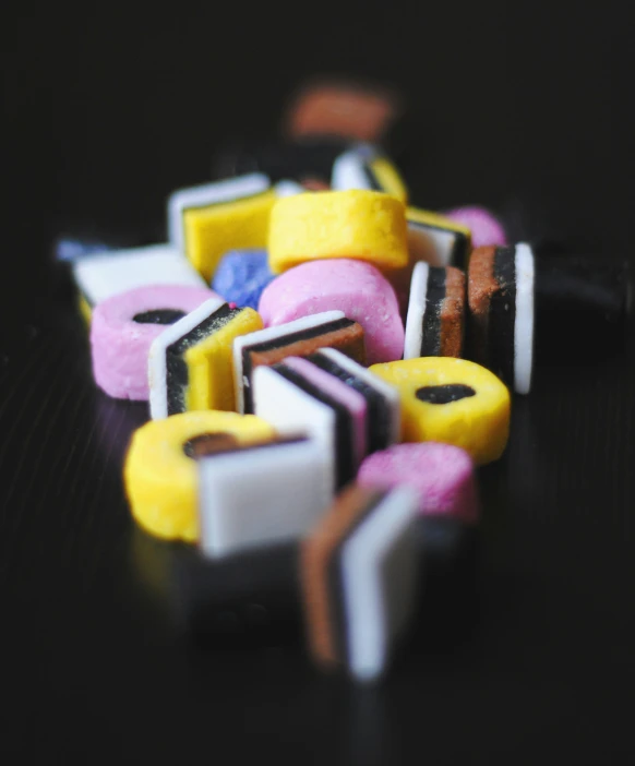 a close up view of some candy with black, pink, and yellow colors