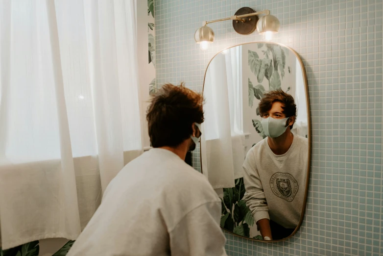 a woman standing in front of a mirror wearing a face mask