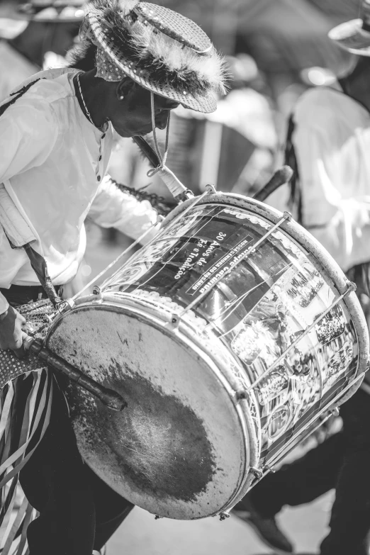 a man playing drums as others in a crowd watch