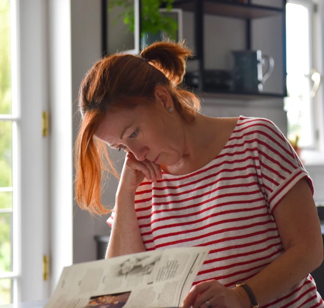 a woman holding a magazine while sitting at a table