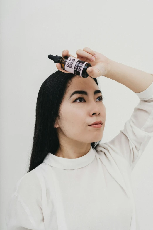 a woman wearing a white shirt holds her hair up to her head