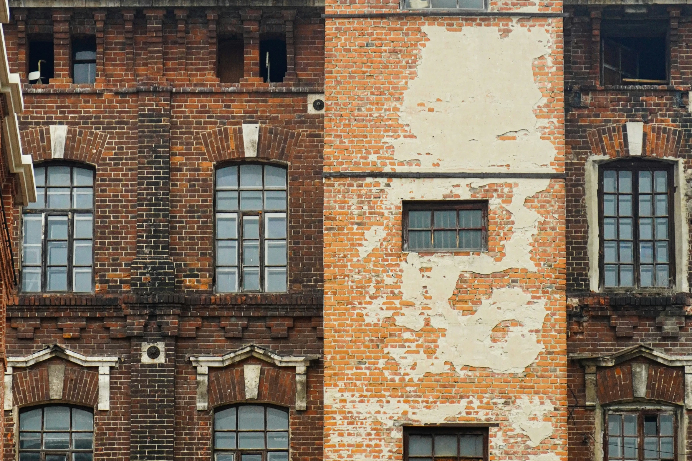 the back of an old building with windows and boarded up windows