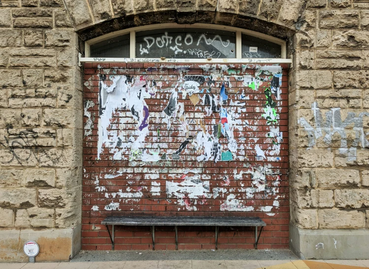 a door with graffiti is next to a bench