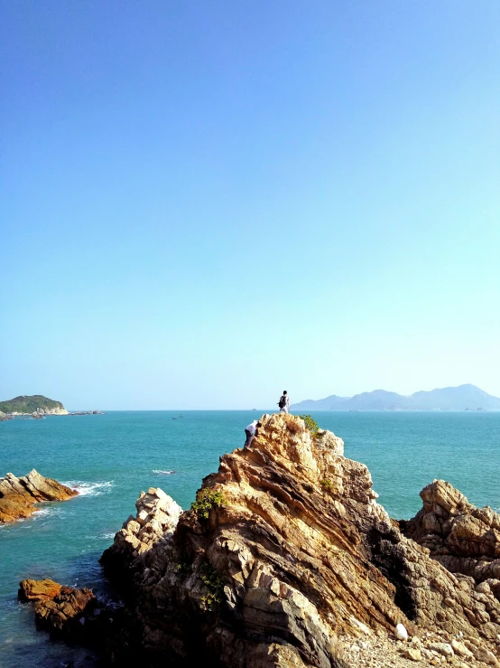 two people on a rocky outcropping looking out at the ocean