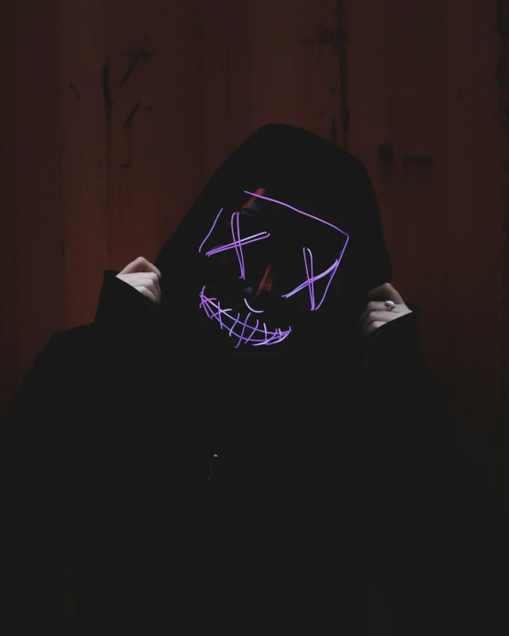 a person wearing a hood and mask with neon paint