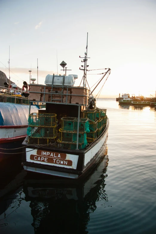 two boats in the water at sunset with fishing nets