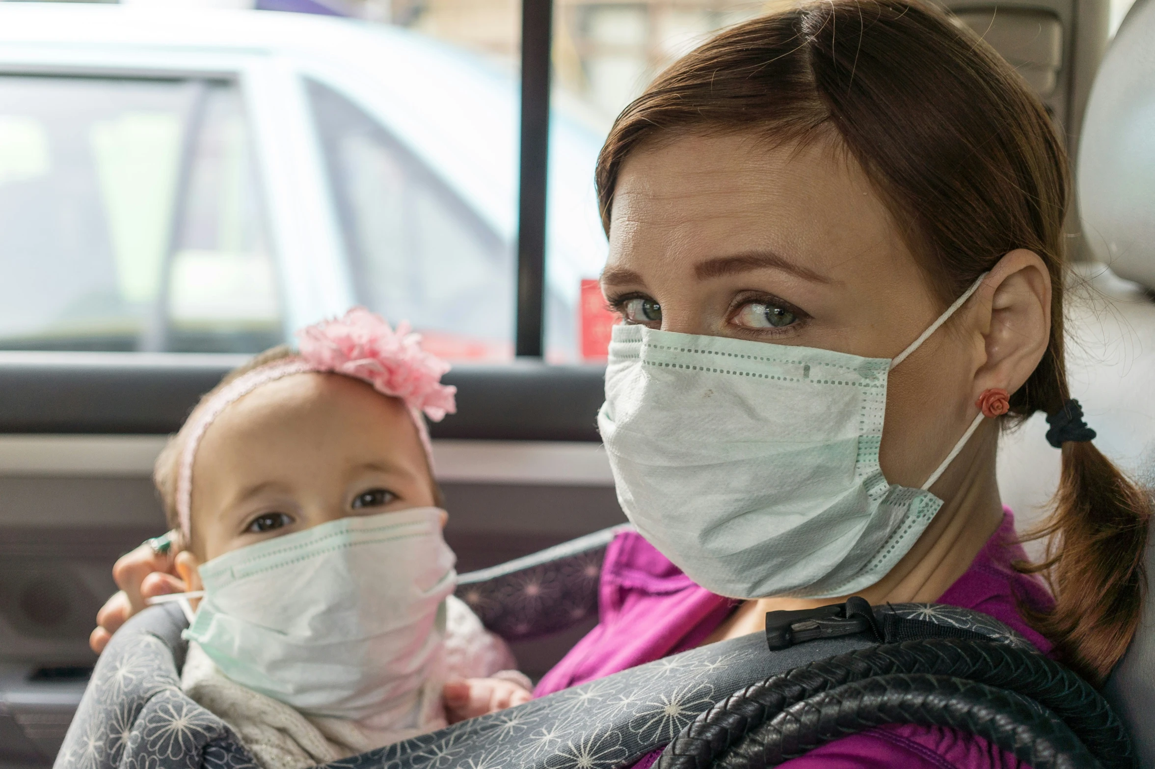 a woman is holding a baby wearing a mask