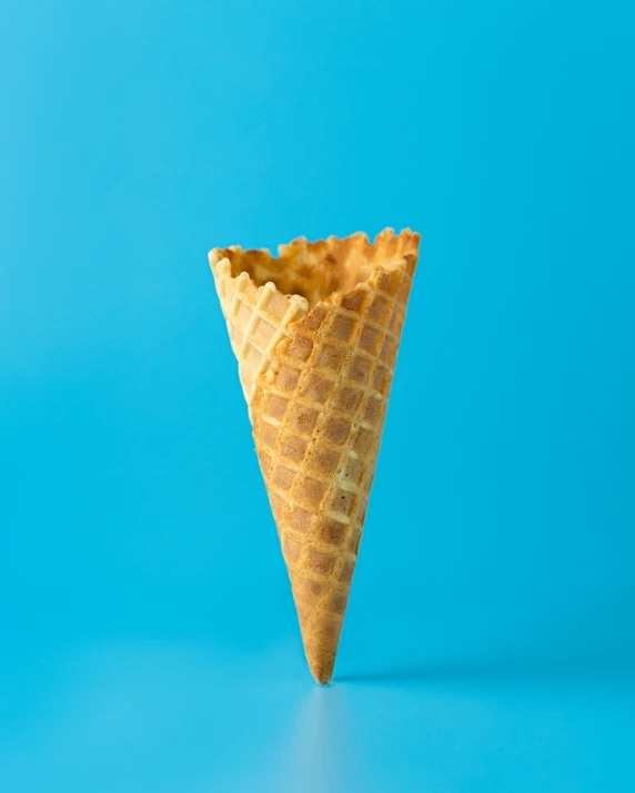 an ice cream cone is leaning sideways on a blue background