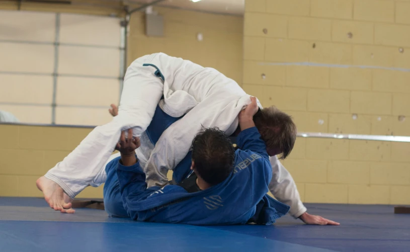 two people practicing karate moves on a blue mat