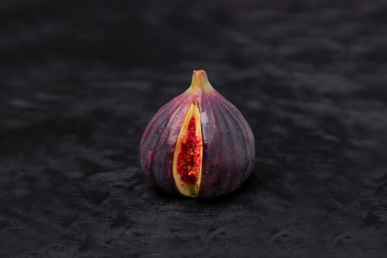 an open fig with a section in the middle sitting on black stone