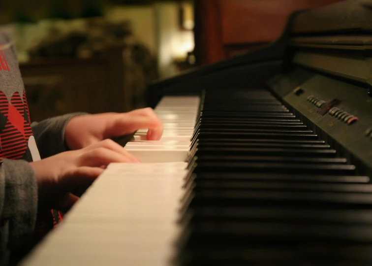 a small child with two hands playing a piano