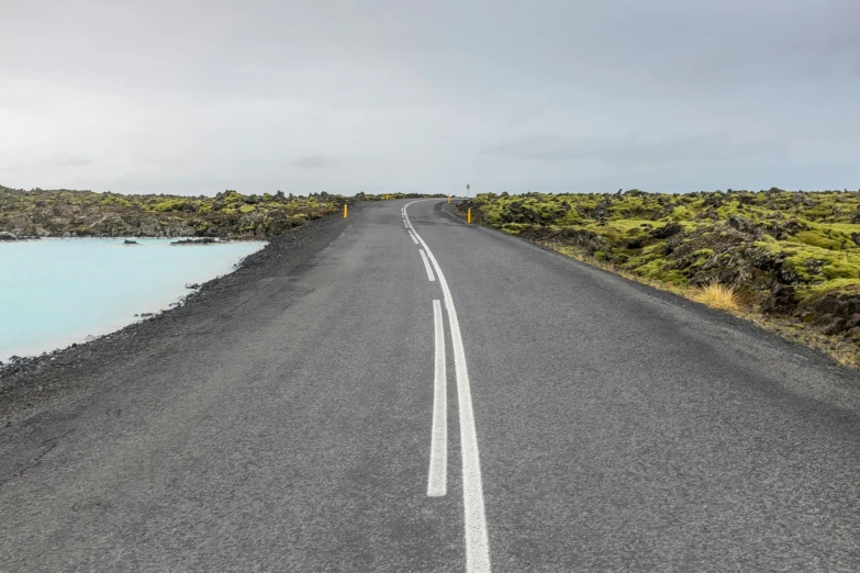 the road is near some water and grass