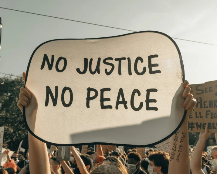 a protester holds a sign with the words no justice, no peace