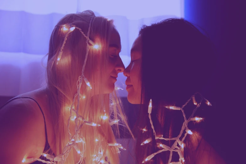 two young woman are standing near one another and kissing