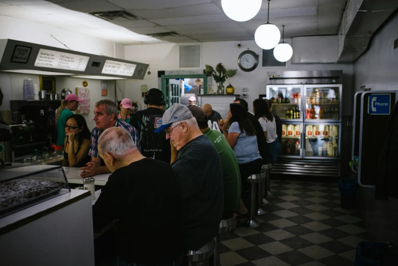 a number of people sitting in a line in front of a fridge