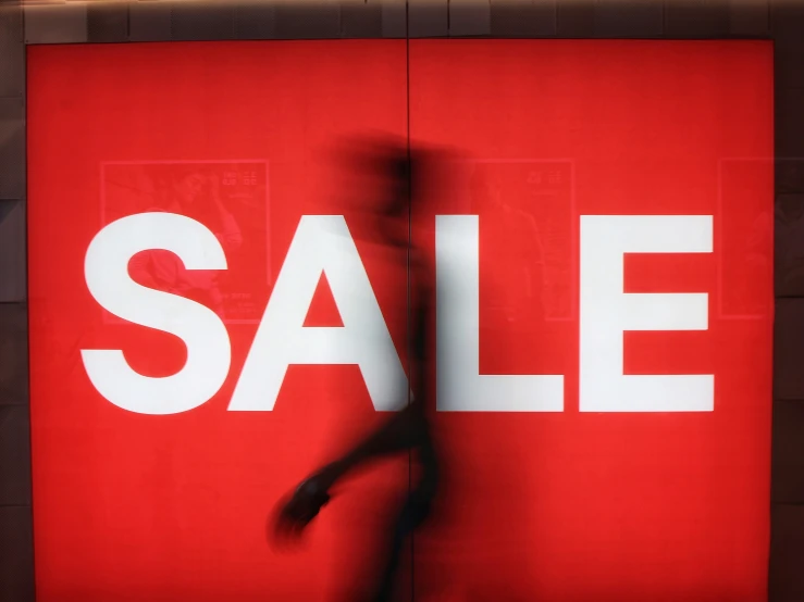 red and white sign with a large sale in the background