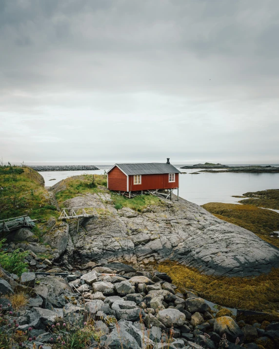 a small house on a rock next to water