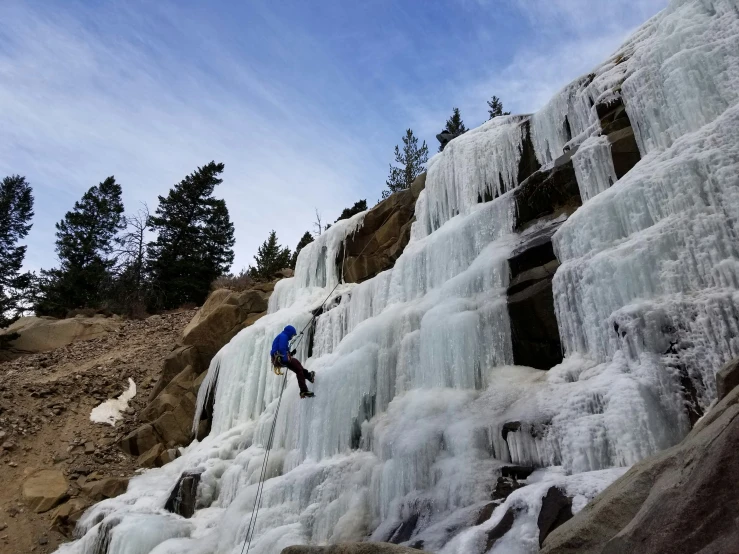 an ice climber climbing up the side of a waterfall